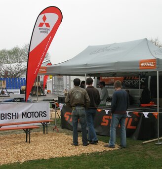 Zwarte 3x4,5 m opvouwbare gazebo gepersonaliseerd met Adidas eyewear logo en gesloten zijwanden. Bordeaux druppelvlaggen met logo. Buitententoonstelling van Adidas brillen. Ecotent
