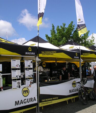 Witte 8x4 m gazebo met gesloten zijwanden en ramen, gepersonaliseerd met tekst voor Beierse Rode Kruis en gepersonaliseerde druppelvlag met logo