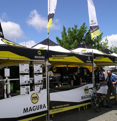 Witte 8x4 m gazebo met gesloten zijwanden en ramen, gepersonaliseerd met tekst voor Beierse Rode Kruis en gepersonaliseerde druppelvlag met logo