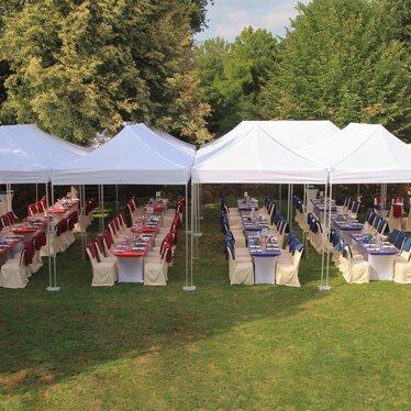 Zwarte 3x3 m gazebo met 2 gesloten zijwanden en een panoramavenster, gepersonaliseerd met Hannibal Gin logo, gebruikt voor ginverkoop op een straatje.