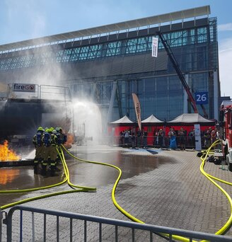 Drie zwarte 3x3 m Ecotent gazebos met rode zijwanden op de Interschutz brandweerbeurs tijdens een noodsituatieoefening